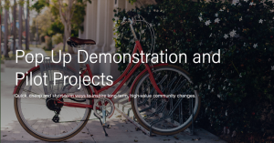 Image of a bike in a bike rack with the text over top that reads "Pop-Up Demonstrations and Pilot Projects"