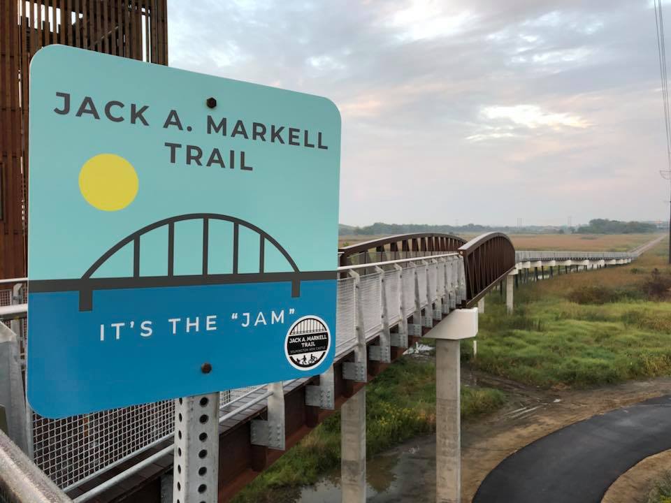 Image of the Jack A. Markell Trail sign and a bridge that forms part of the trail.
