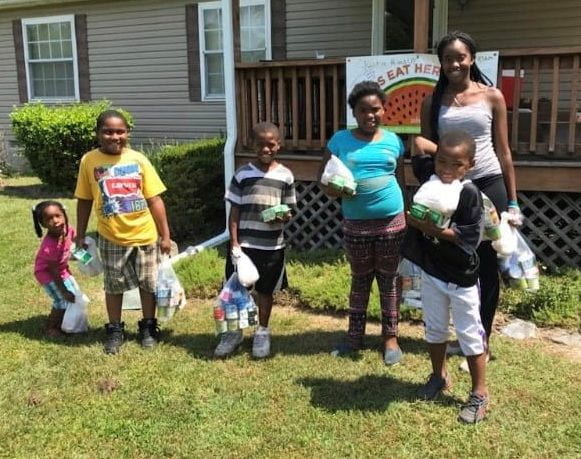 Image of kids showing off their summer grab and go meals from the Summer Nutrition Program at Coverdale Crossroads in Bridgeville.