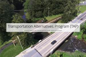 A rendering of a pedestrian and bike bridge crossing the creek next to the vehicle bridge, with the text "Transportation Alternative Program (TAP) overtop in black text.